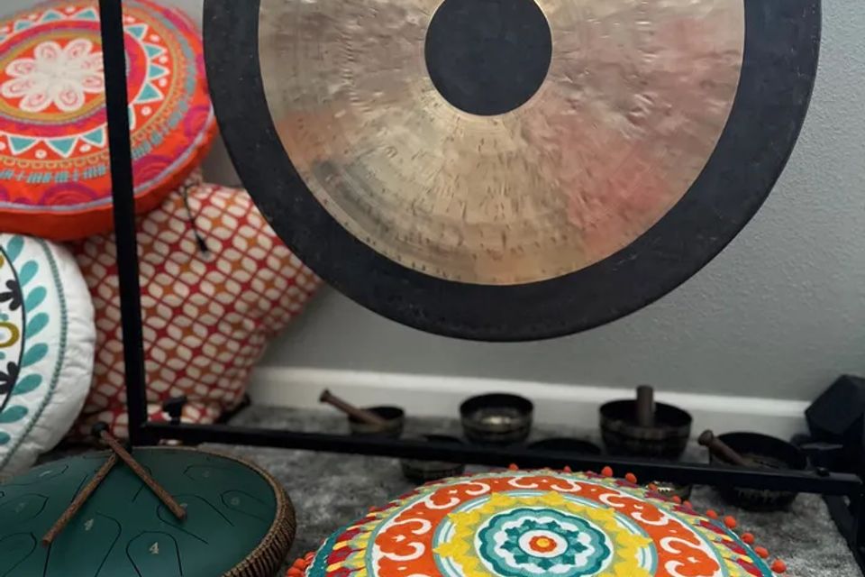 A gong on its stand beside floor cushions in the studio